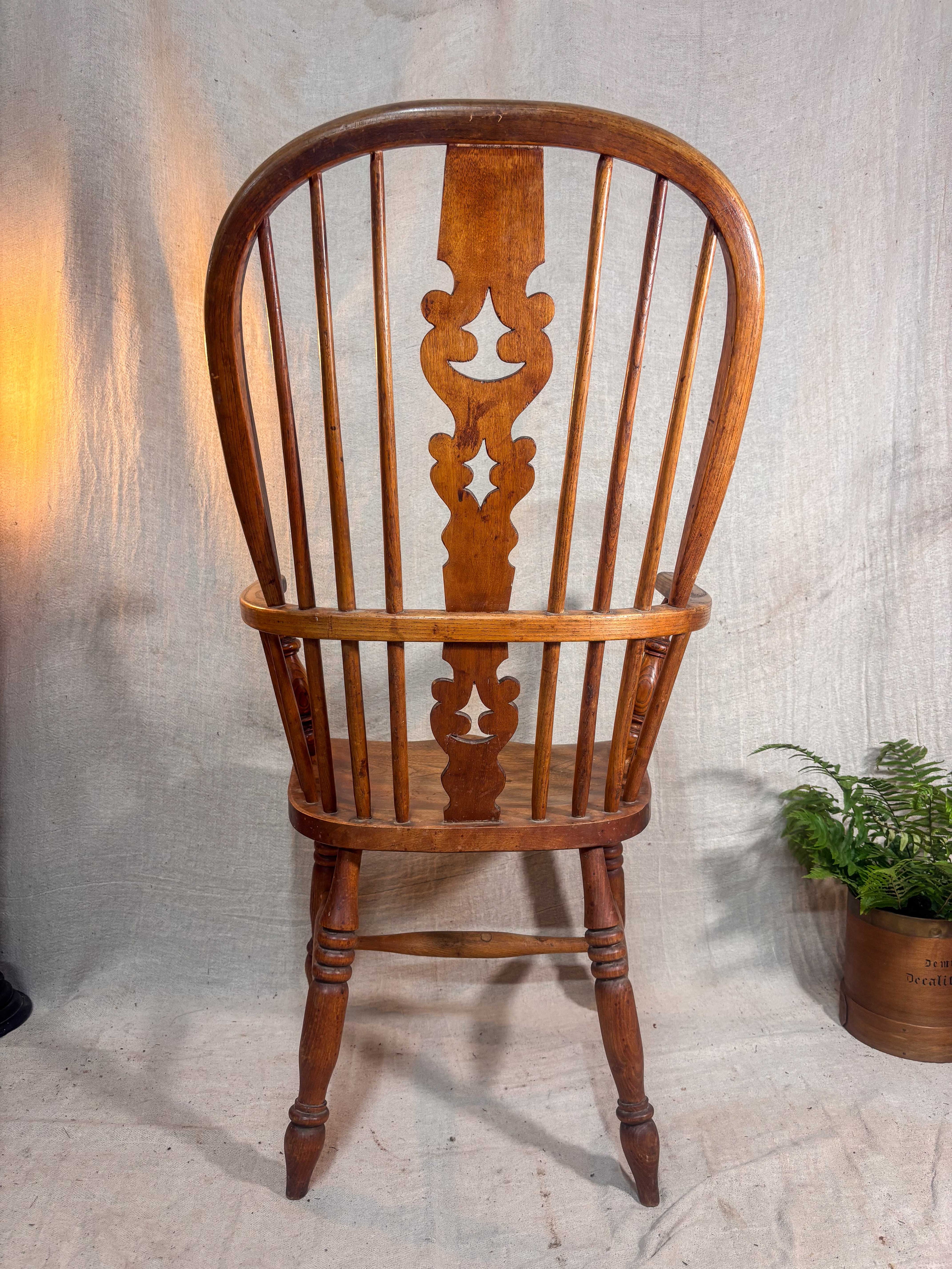 Wooden chair with intricate back design on a textured wall background