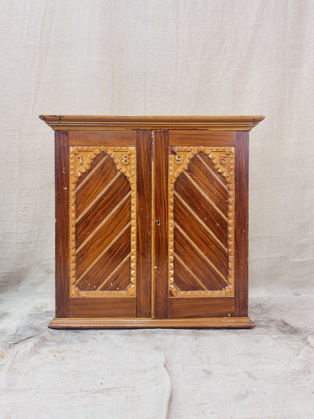 Wooden cabinet with decorative carvings on a plain background