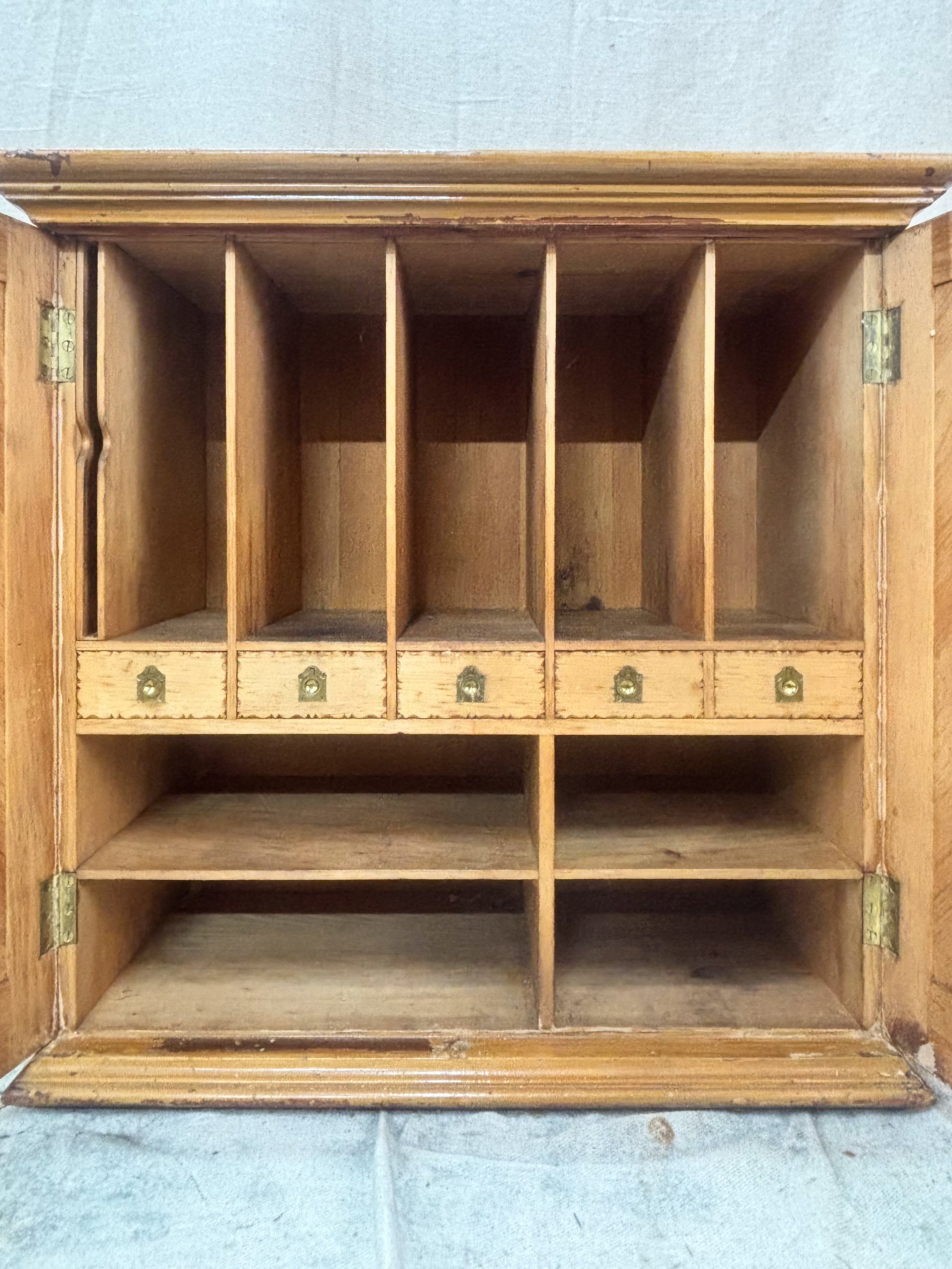 Wooden cabinet with multiple shelves and small drawers on a concrete floor.