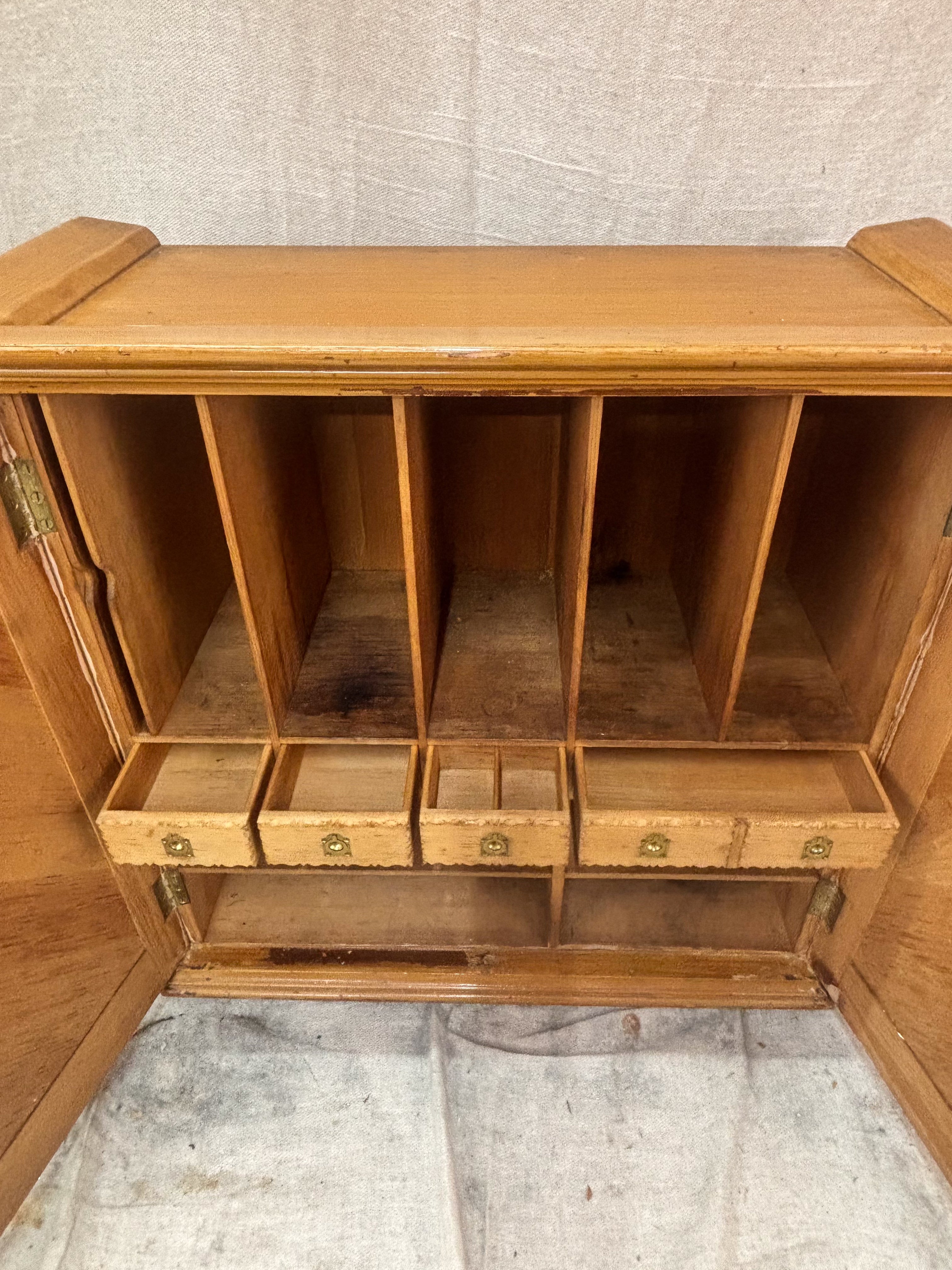 Wooden cabinet with multiple compartments and drawers against a beige wall.