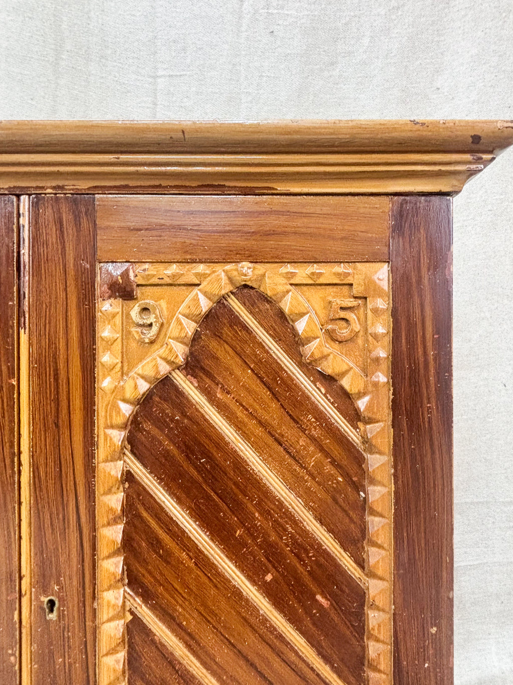 Close-up of a wooden panel with intricate carvings on a textured white background