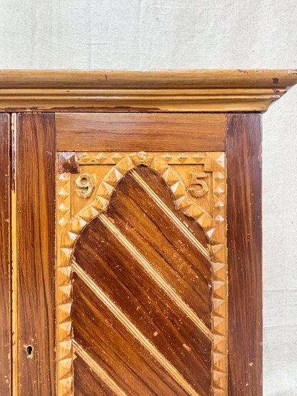 Close-up of a wooden panel with intricate carvings on a textured white background