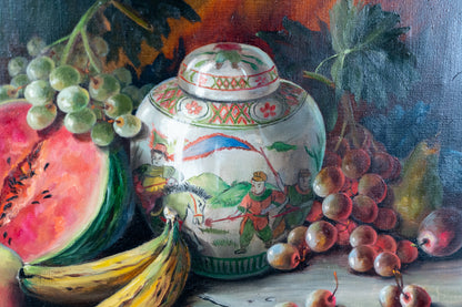 A still life painting featuring a decorative white ceramic jar with painted figures and patterns, surrounded by green grapes, red grapes, a sliced watermelon, bananas, and pears on a dark painted background.