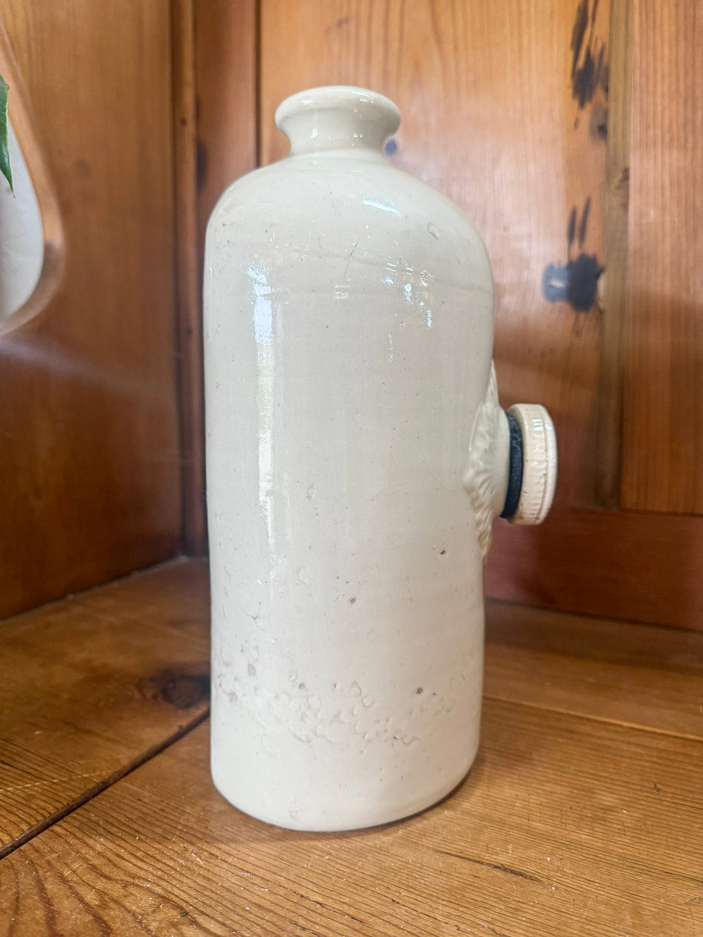 White ceramic hot water bottle on a wooden surface