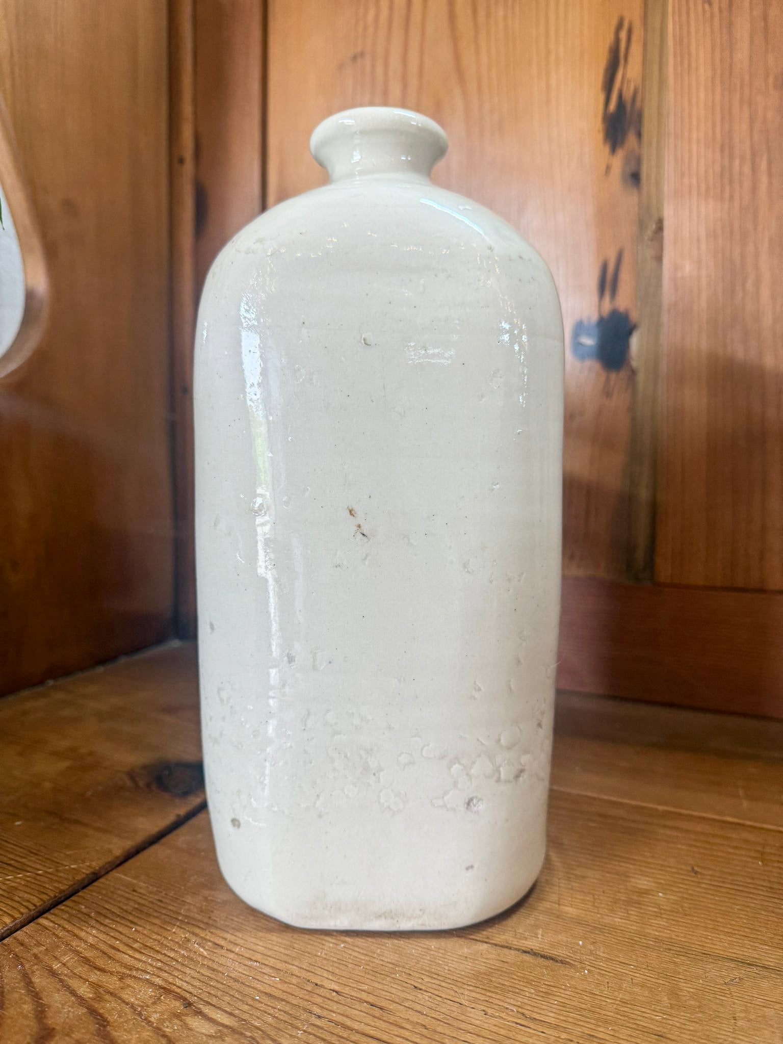 White ceramic hot water bottle on a wooden surface