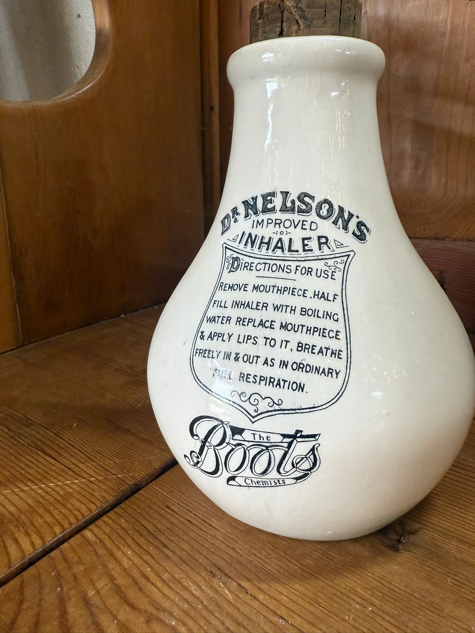 Vintage-style ceramic inhaler with 'D. Nelson's Improved Inhaler' label on a wooden surface.