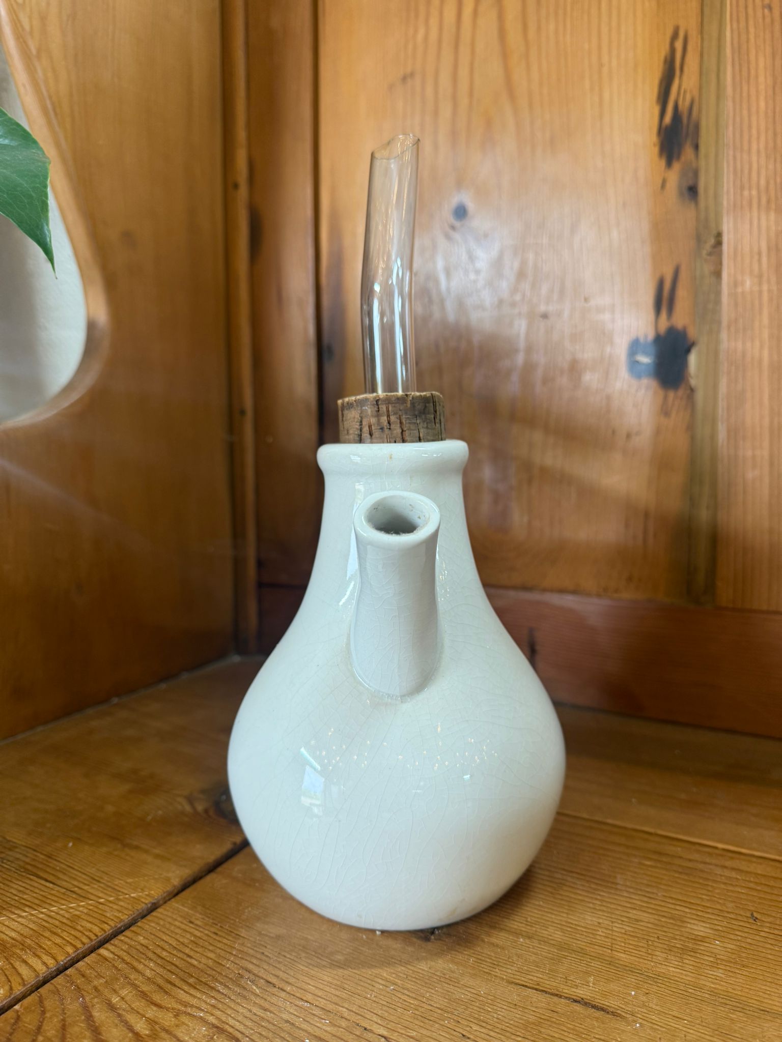 White ceramic bottle with a wooden cap on a wooden surface