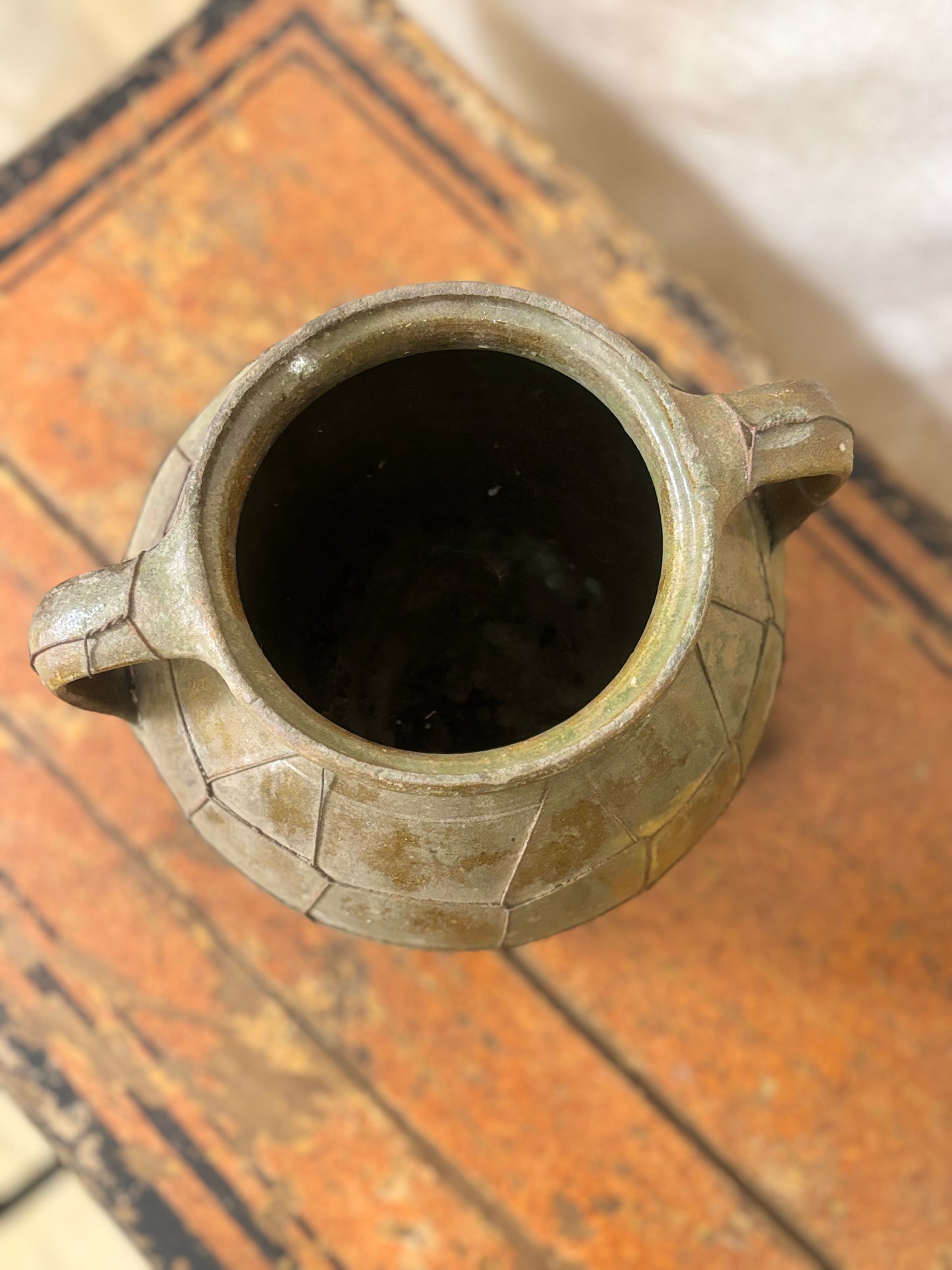Ceramic vase with two handles on a wooden surface