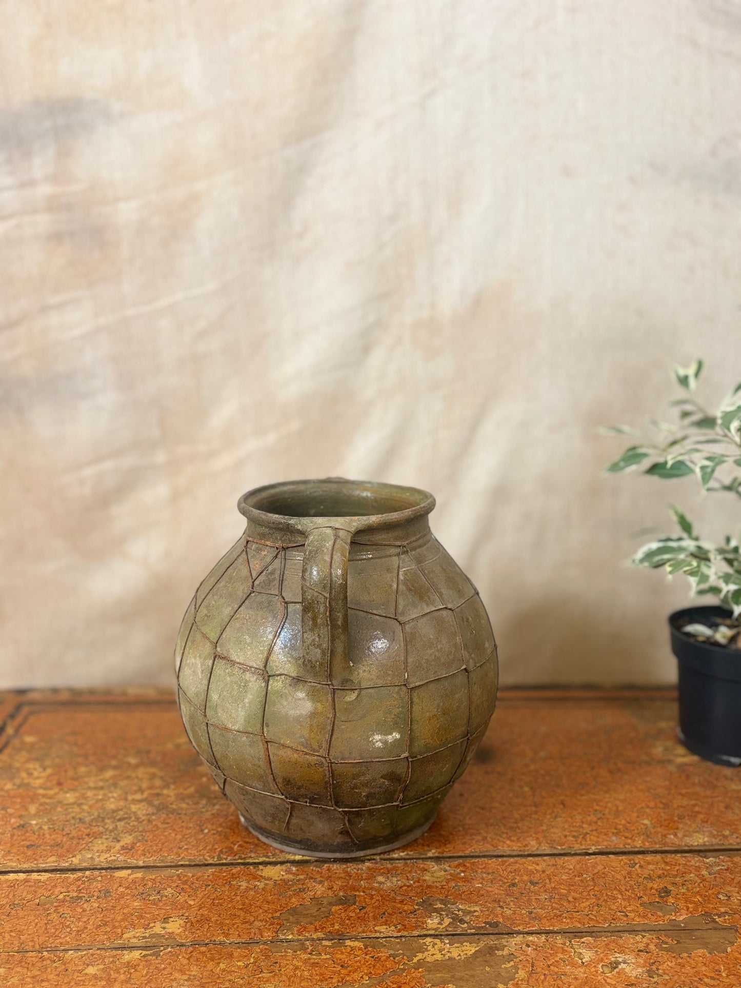 Vintage green ceramic vase on a wooden surface with a neutral background