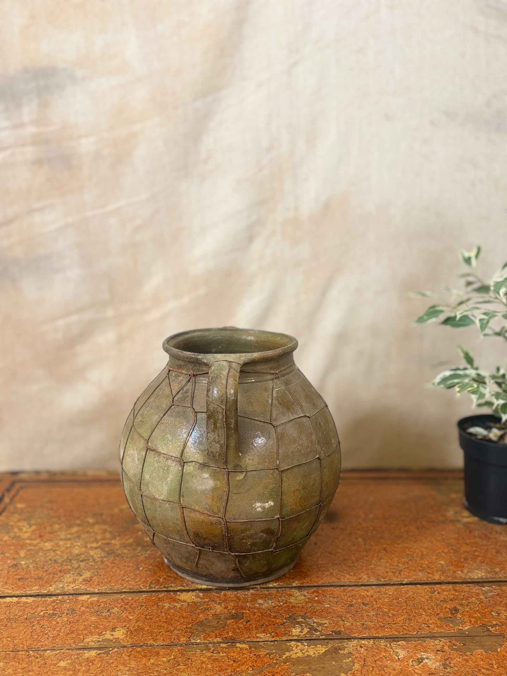Vintage green ceramic vase on a wooden surface with a neutral background