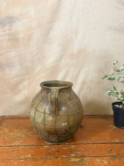 Vintage green ceramic vase on a wooden surface with a neutral background