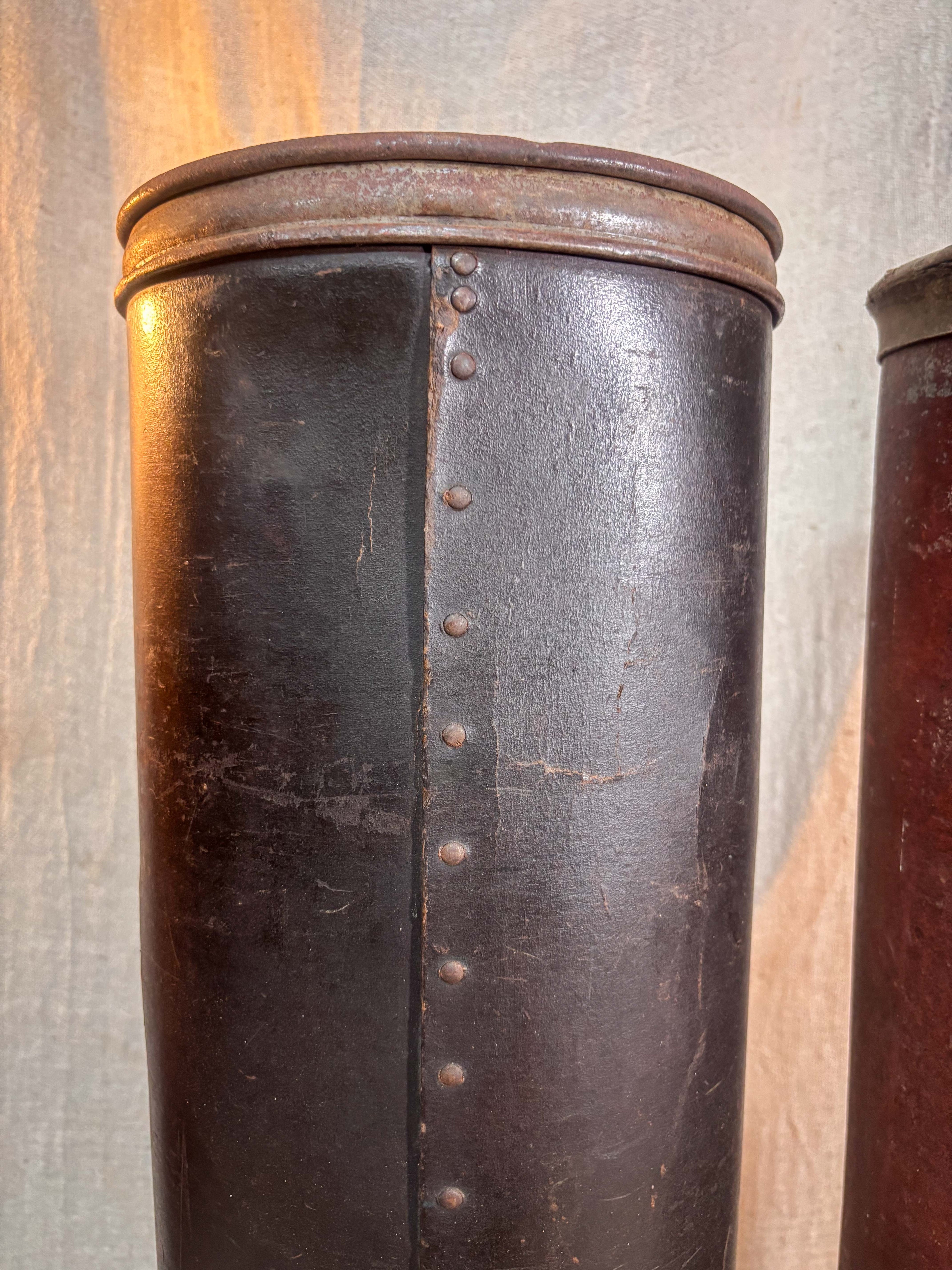 Close-up of a dark brown tube with metal studs against a textured wall.
