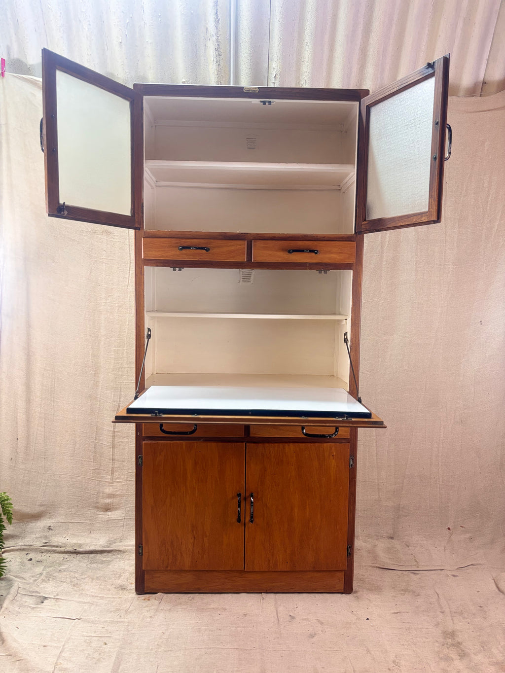 Wooden cabinet with open doors and drawers against a plain background