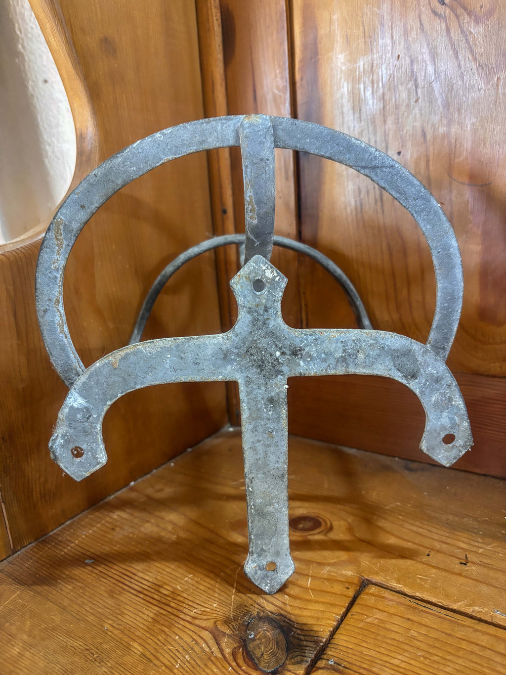 Metal decorative bracket with a cross design on a wooden surface