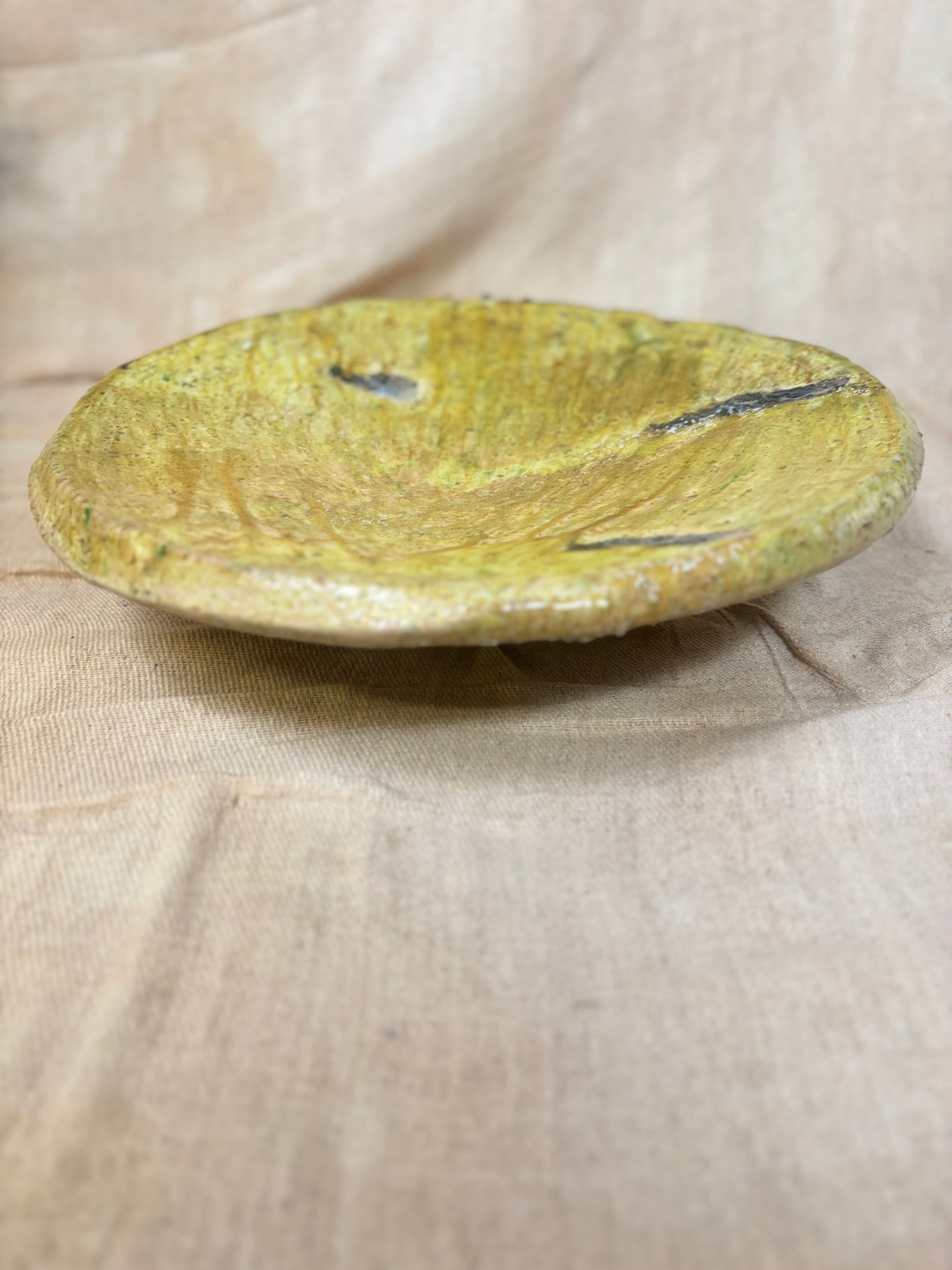 Round yellowish plate on a beige fabric background