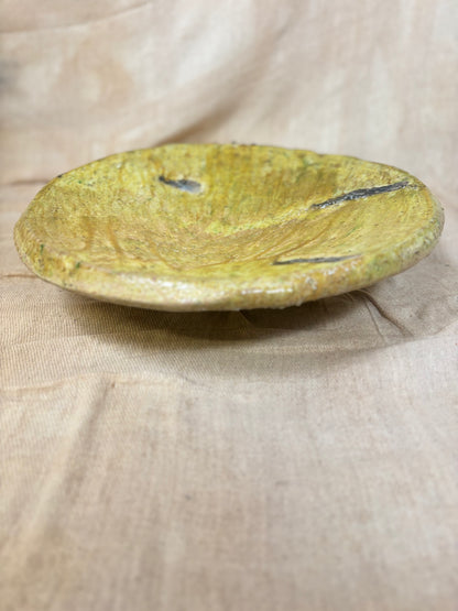 Round yellowish plate on a beige fabric background