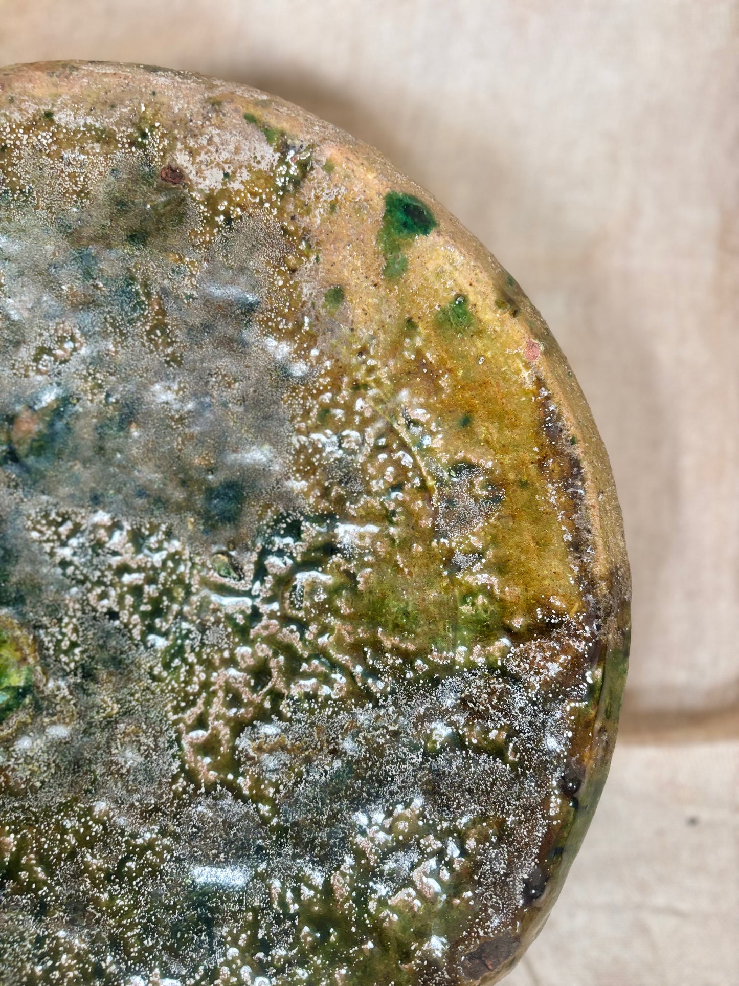 Close-up of a textured stone with green and brown colors on a beige background