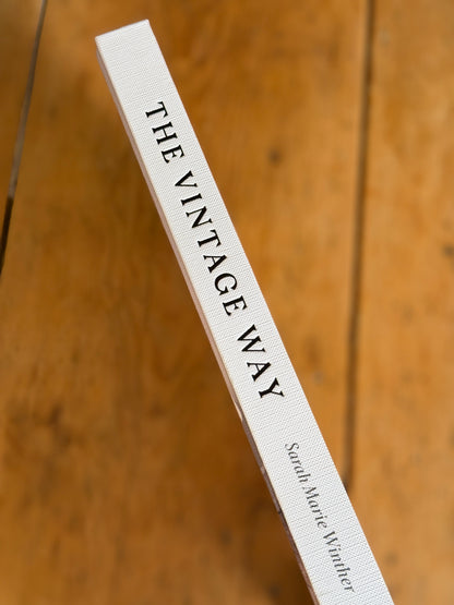 A close-up of a book spine titled 'THE VINTAGE WAY' by Sarah Marie Hunter, resting diagonally on a warm wooden surface.