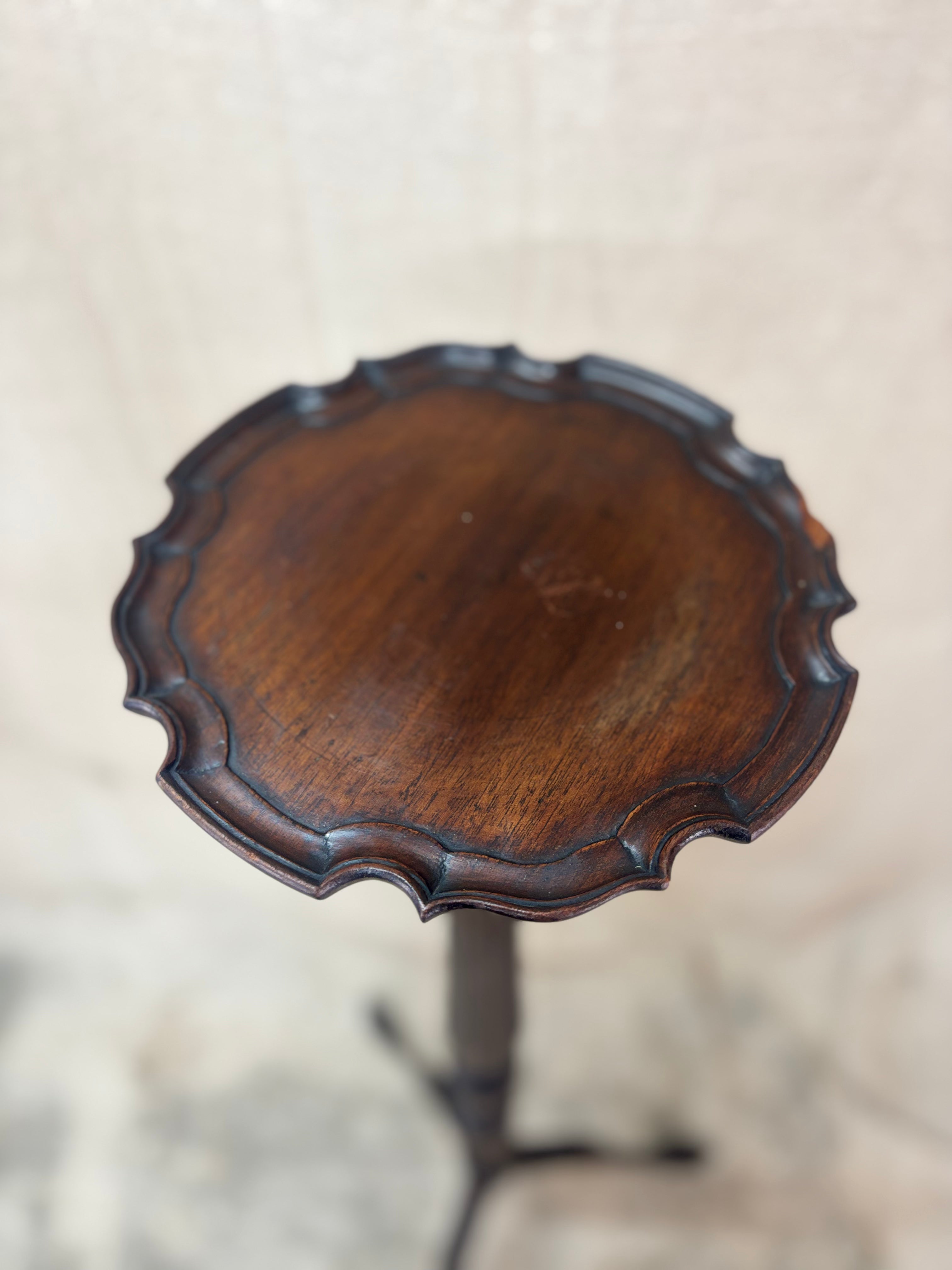 Wooden side table with scalloped edge on a neutral background