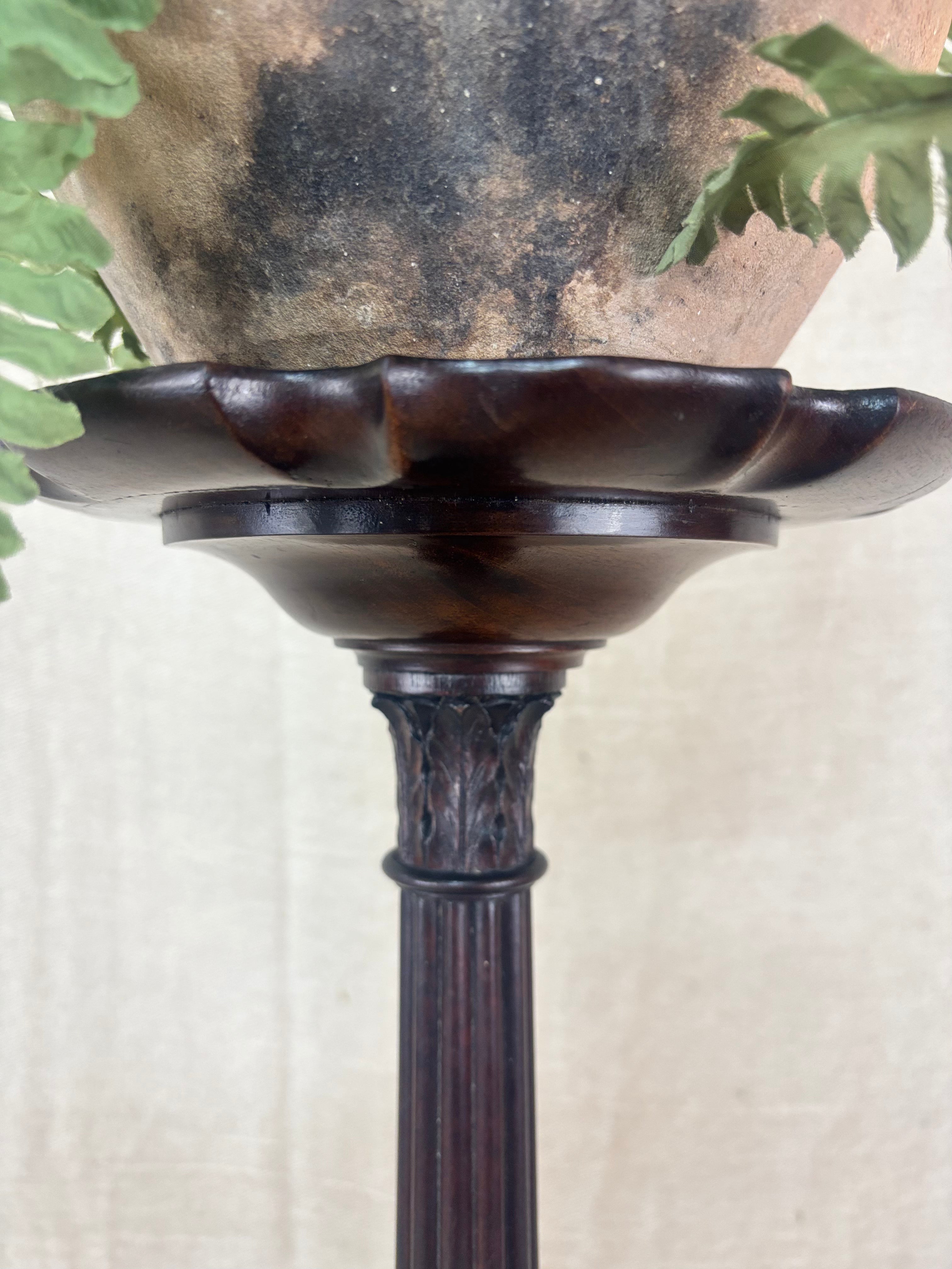 Decorative dark brown pedestal with scalloped edge design against a neutral background