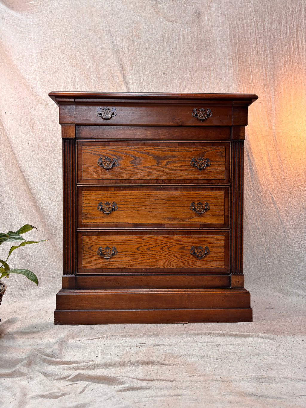Wooden dresser with four drawers on a neutral background