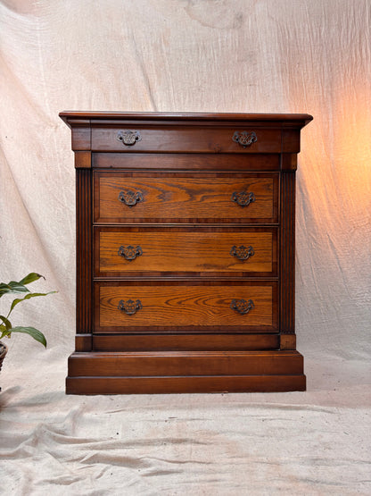 Wooden dresser with four drawers on a neutral background