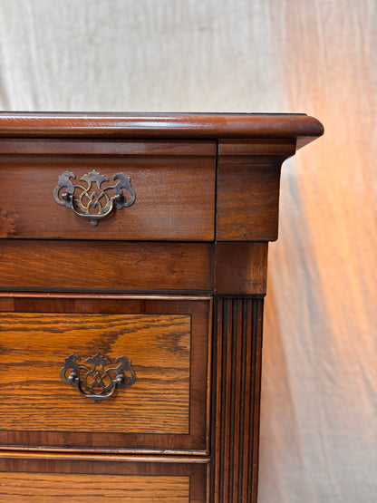 Wooden dresser with two drawers and decorative handles on a white background