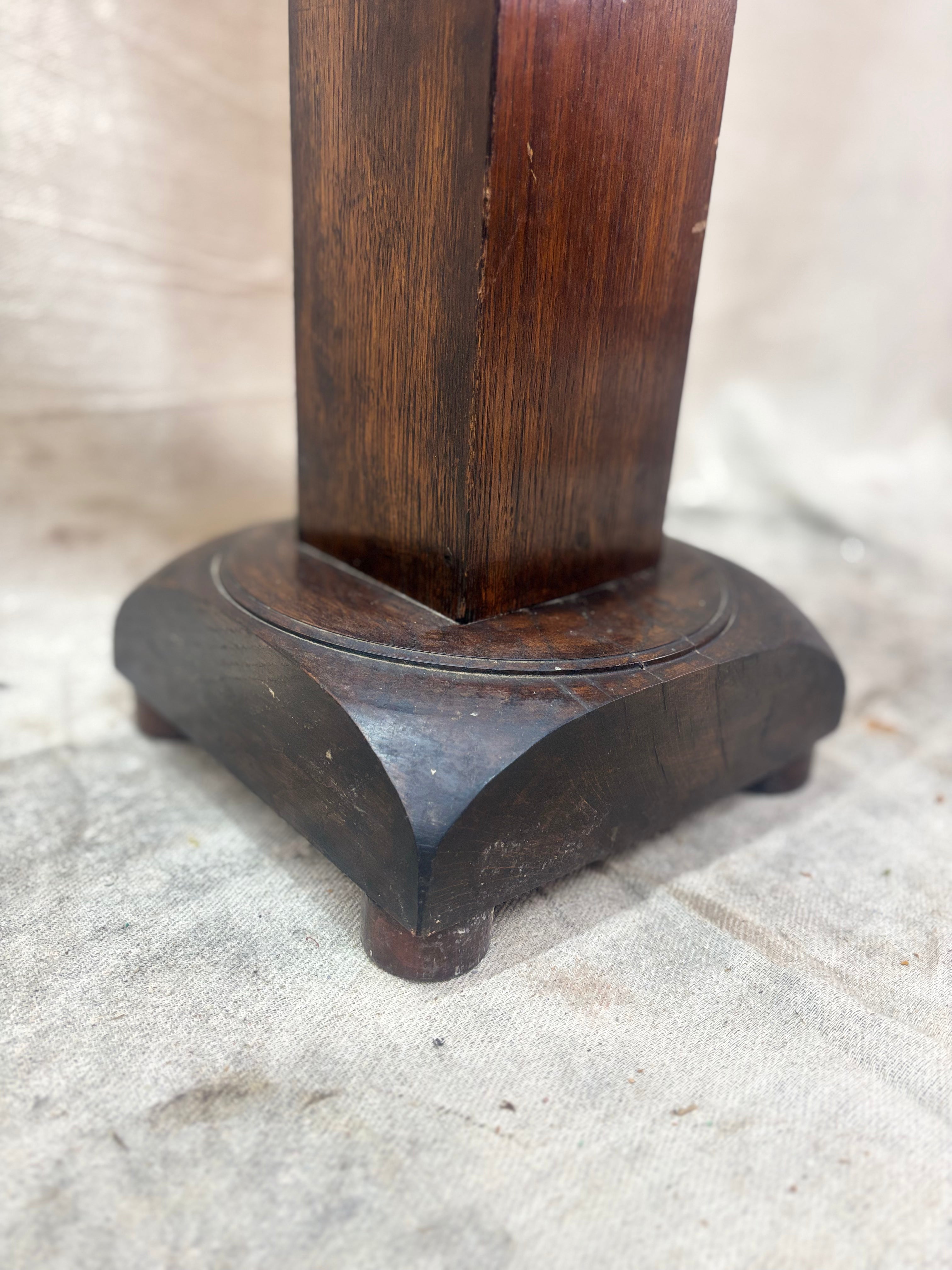 A tall, dark wooden pedestal or plant stand featuring a prominent barley twist central column and a square base.