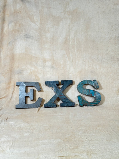 Three rustic metal letters spelling 'EXS' 
