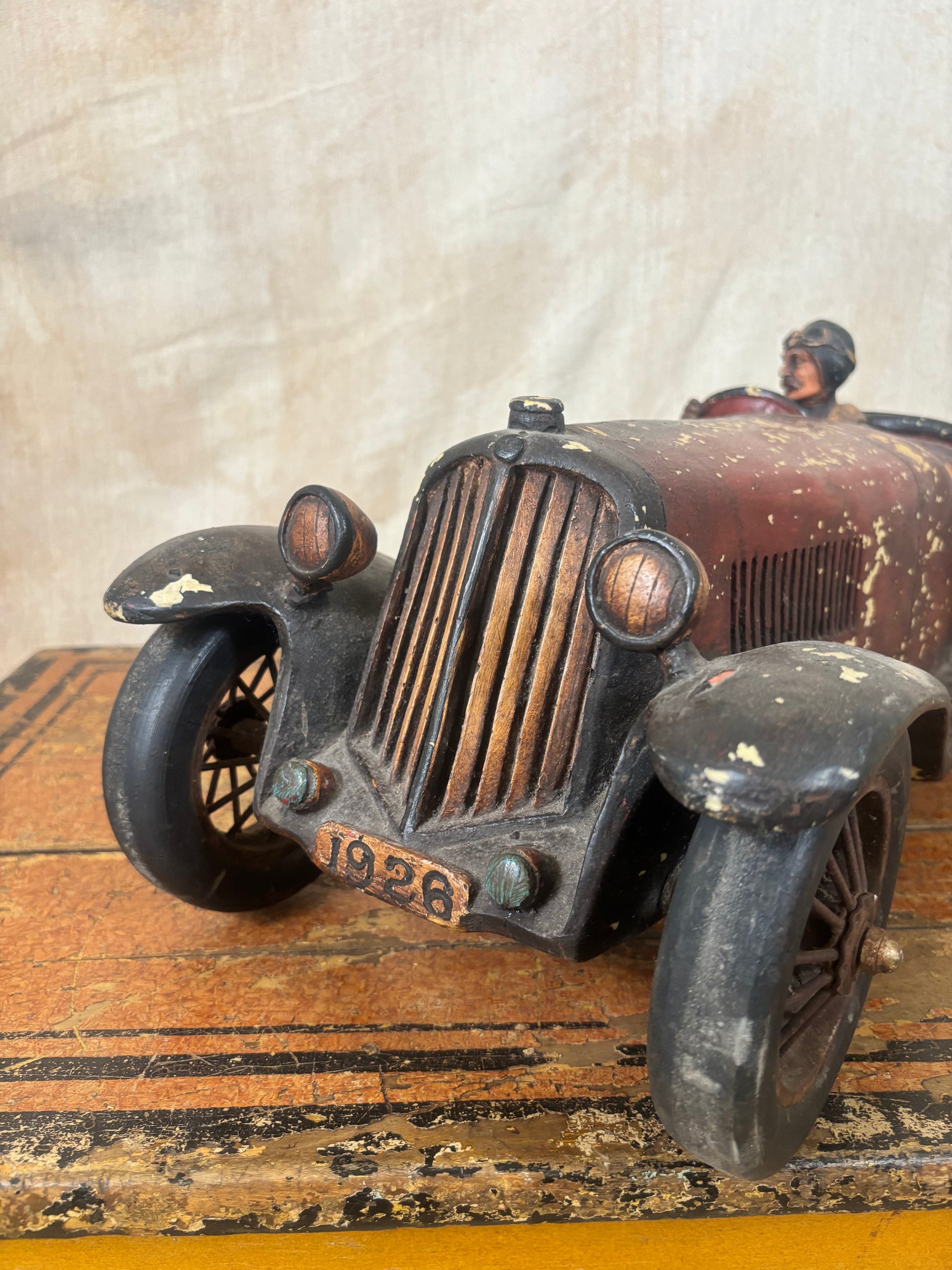 Vintage-style toy car model on a wooden surface with a textured background