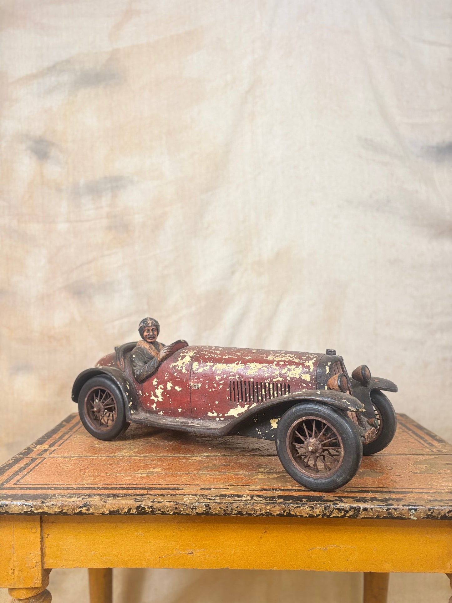 Vintage-style toy car with a driver figure on a wooden surface