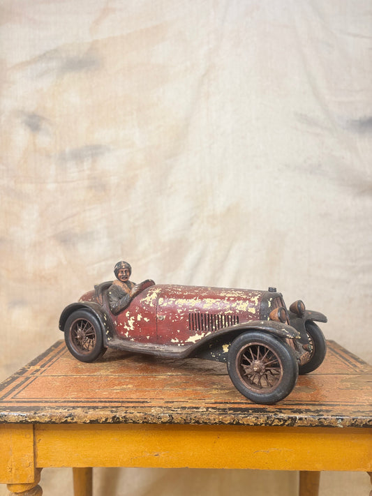 Vintage-style toy car with a driver figure on a wooden surface