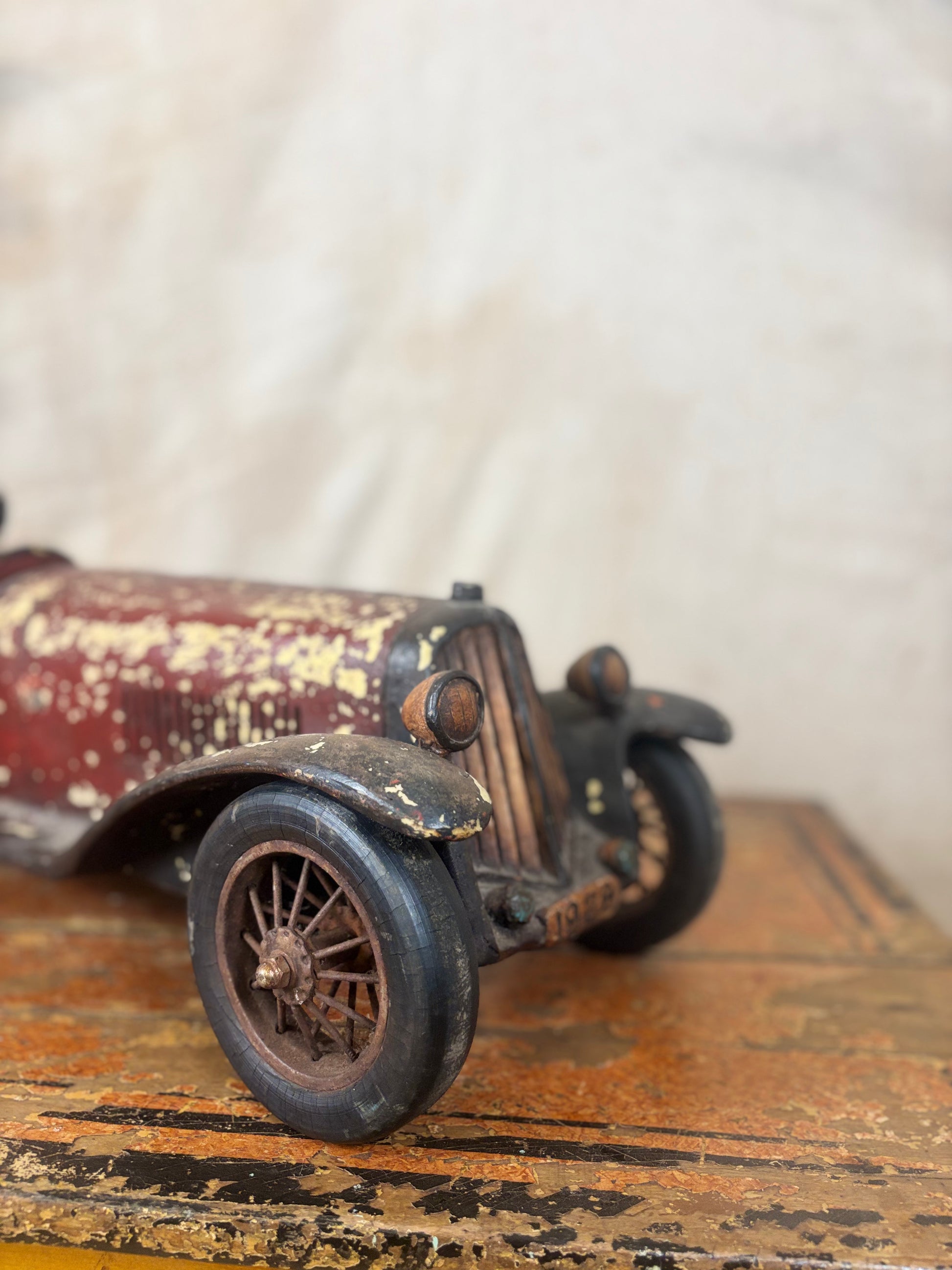 Vintage toy car with rust and wear on a wooden surface