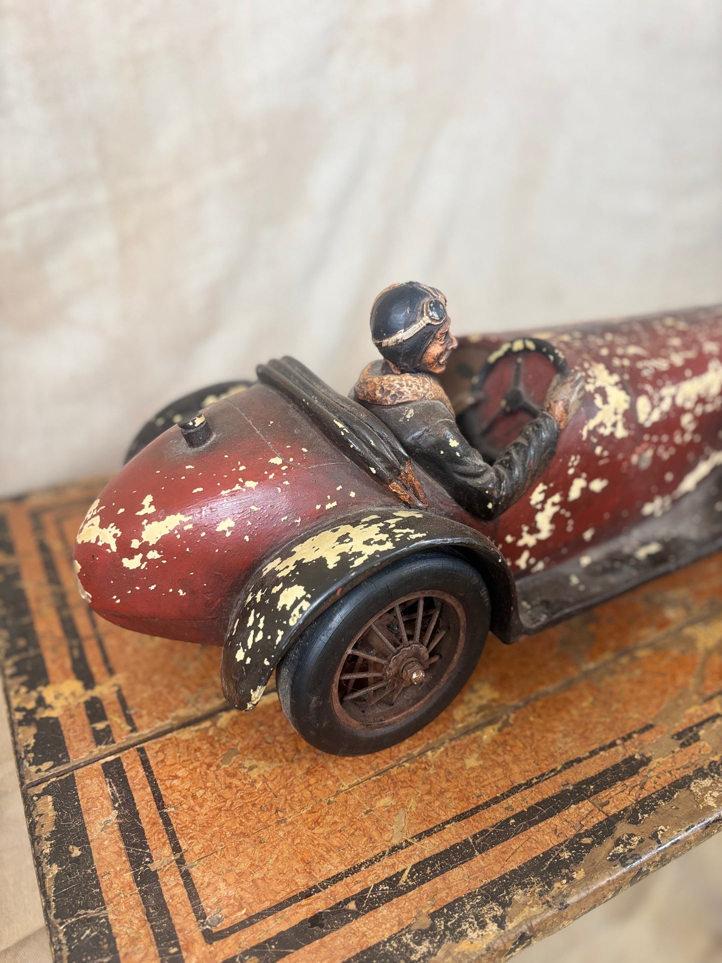 Vintage toy car with a driver figure on a textured surface
