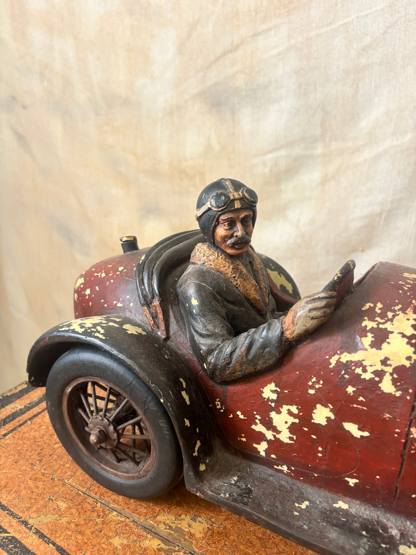 Vintage-style toy car with a driver figure on a textured surface
