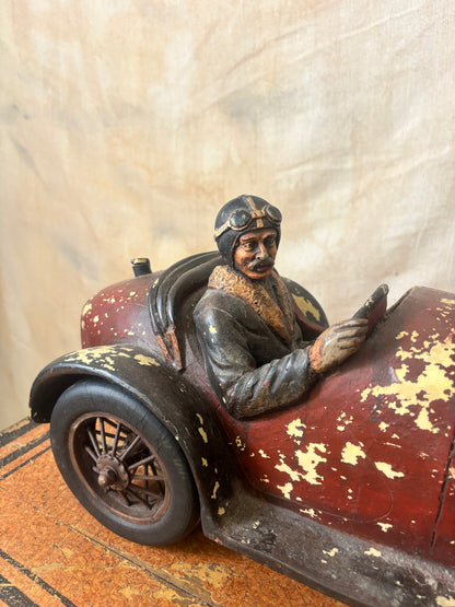 Vintage-style toy car with a driver figure on a textured surface