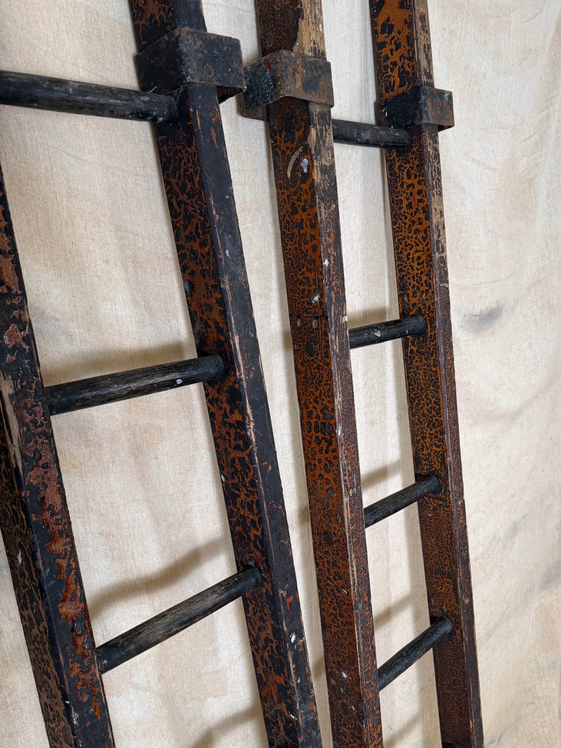 Pair of vintage wooden ladders with worn black paint
