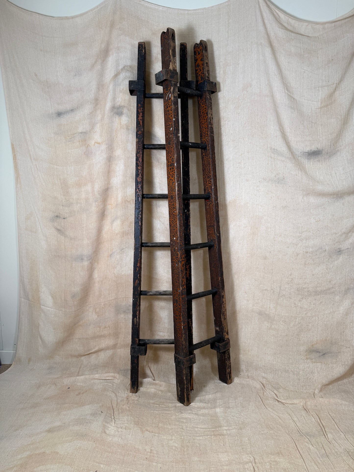 Pair of vintage wooden ladders with worn black paint
