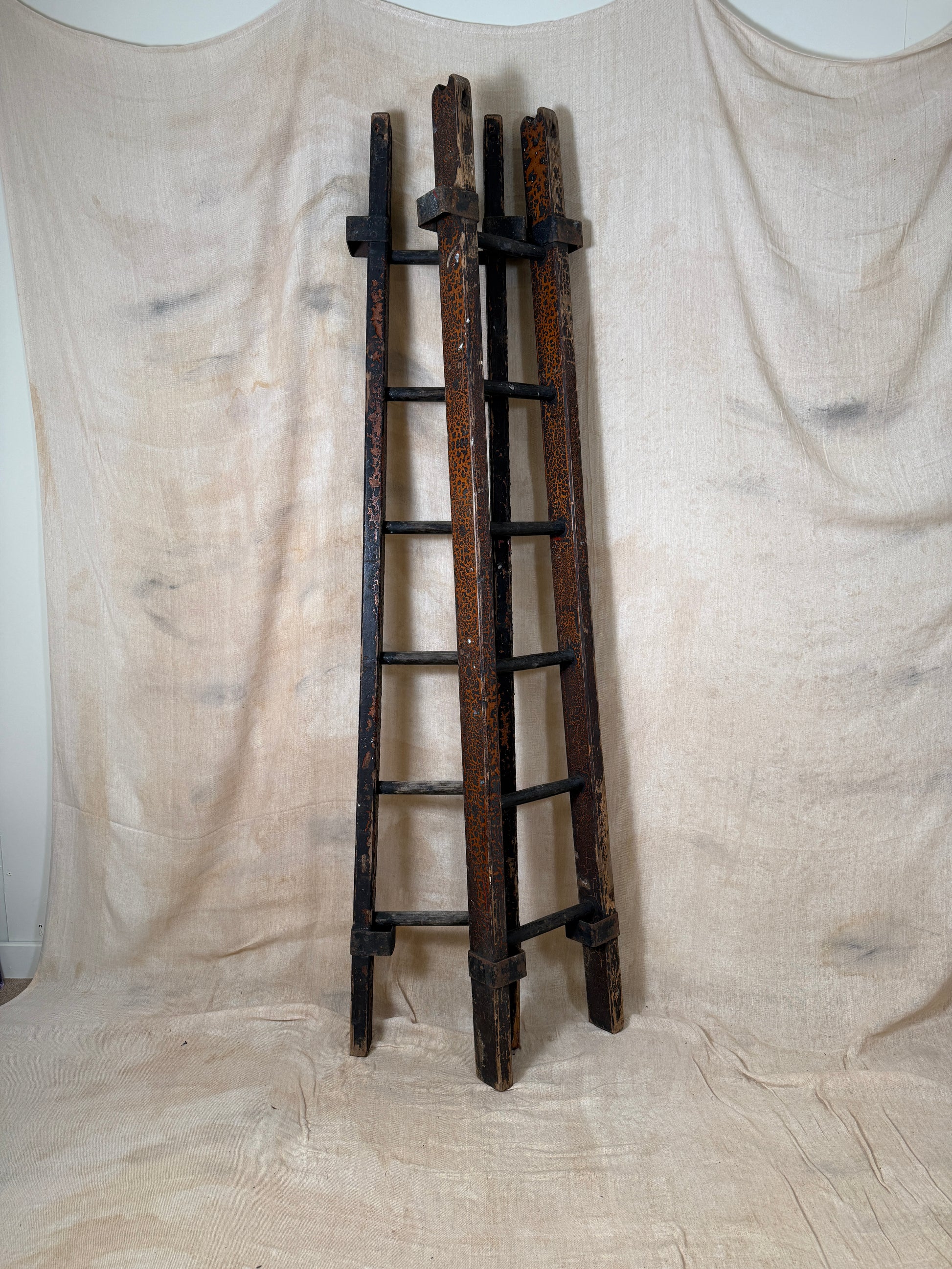 Pair of vintage wooden ladders with worn black paint