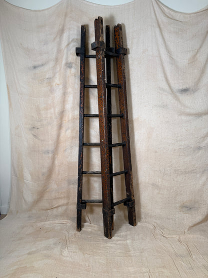 Pair of vintage wooden ladders with worn black paint