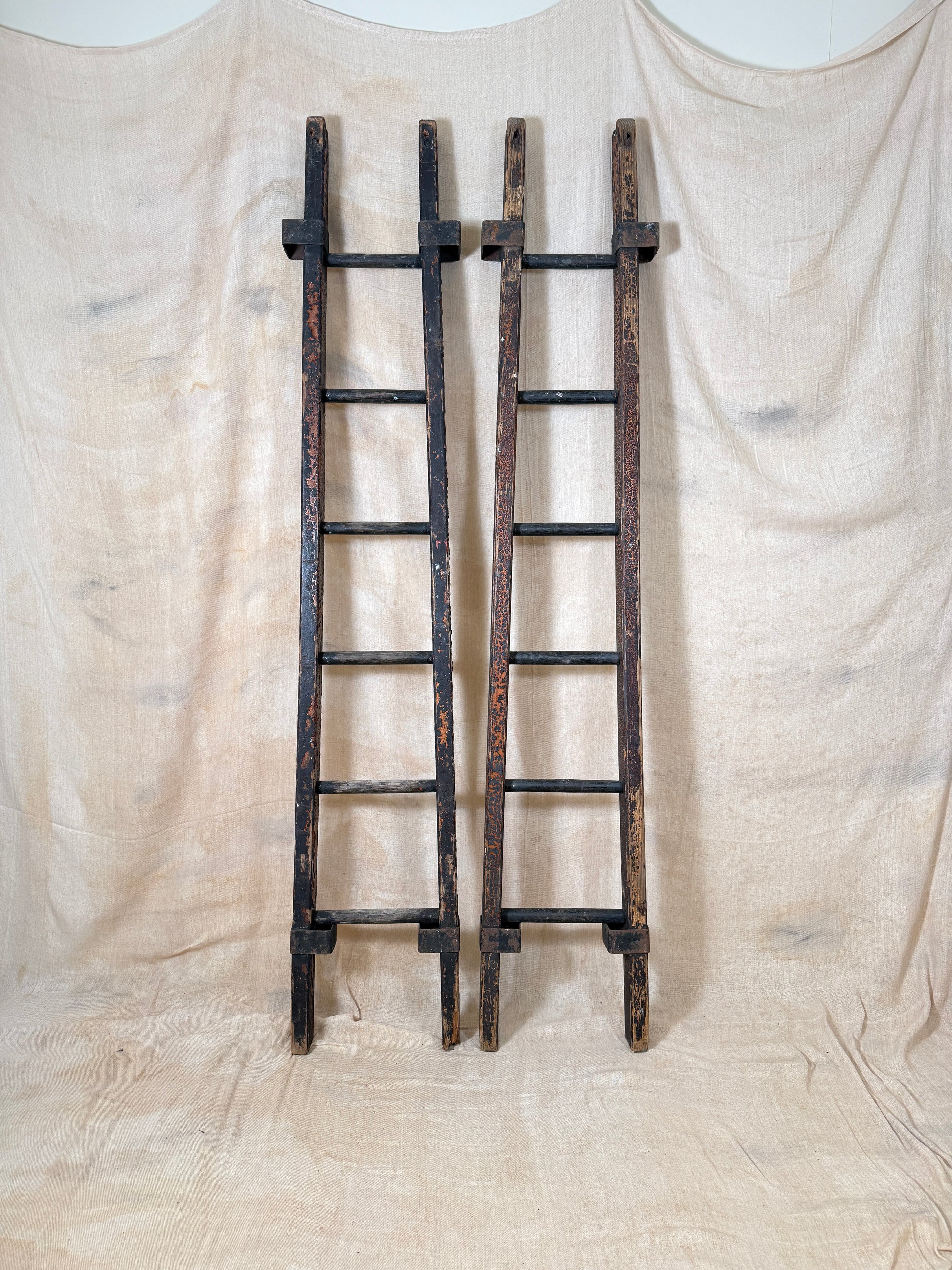 Pair of vintage wooden ladders with worn black paint