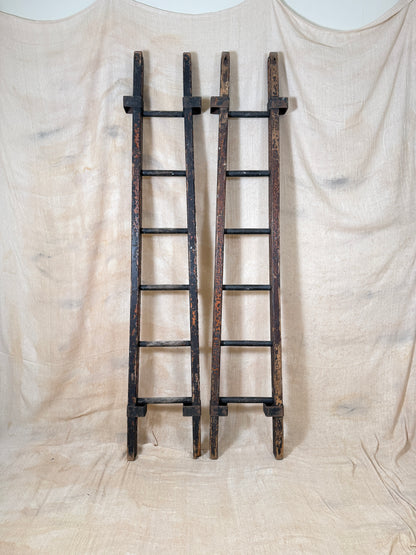 Pair of vintage wooden ladders with worn black paint