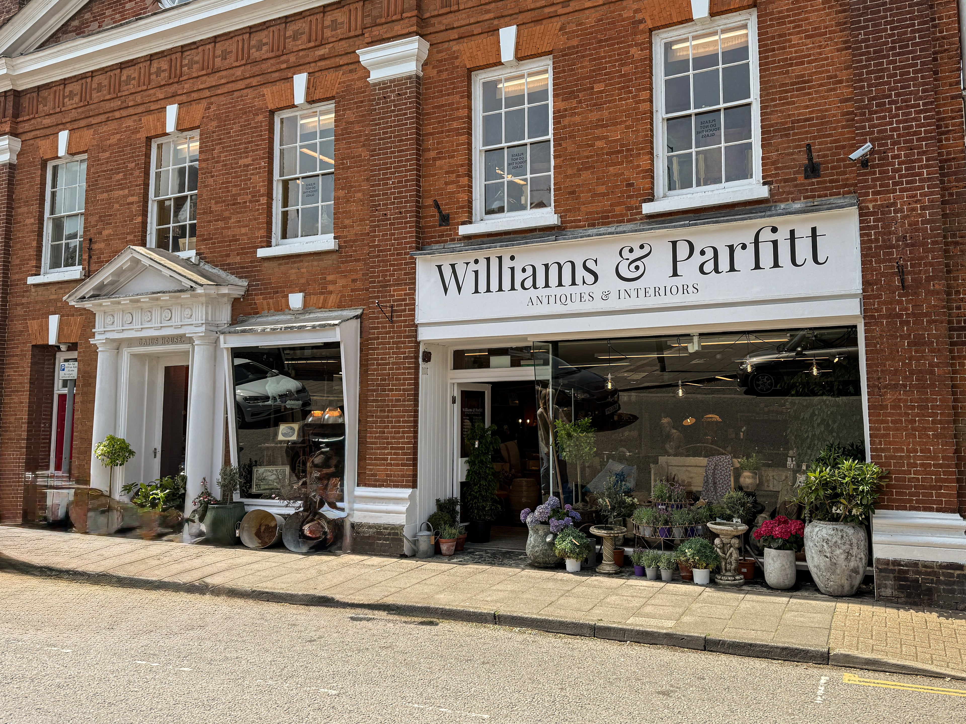 Williams & Parfitt store front with brick building and display of plants and antiques.