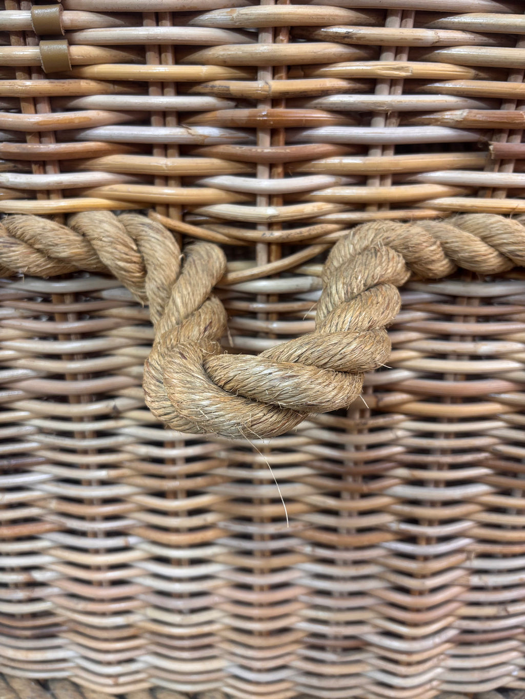 Large wicker storage basket with lid and rope banding, photographed against a neutral backdrop.