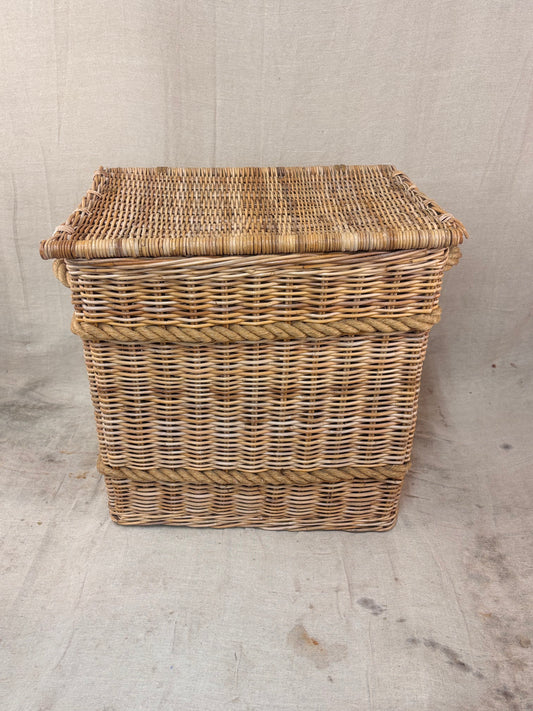 Large wicker storage basket with lid and rope banding, photographed against a neutral backdrop.