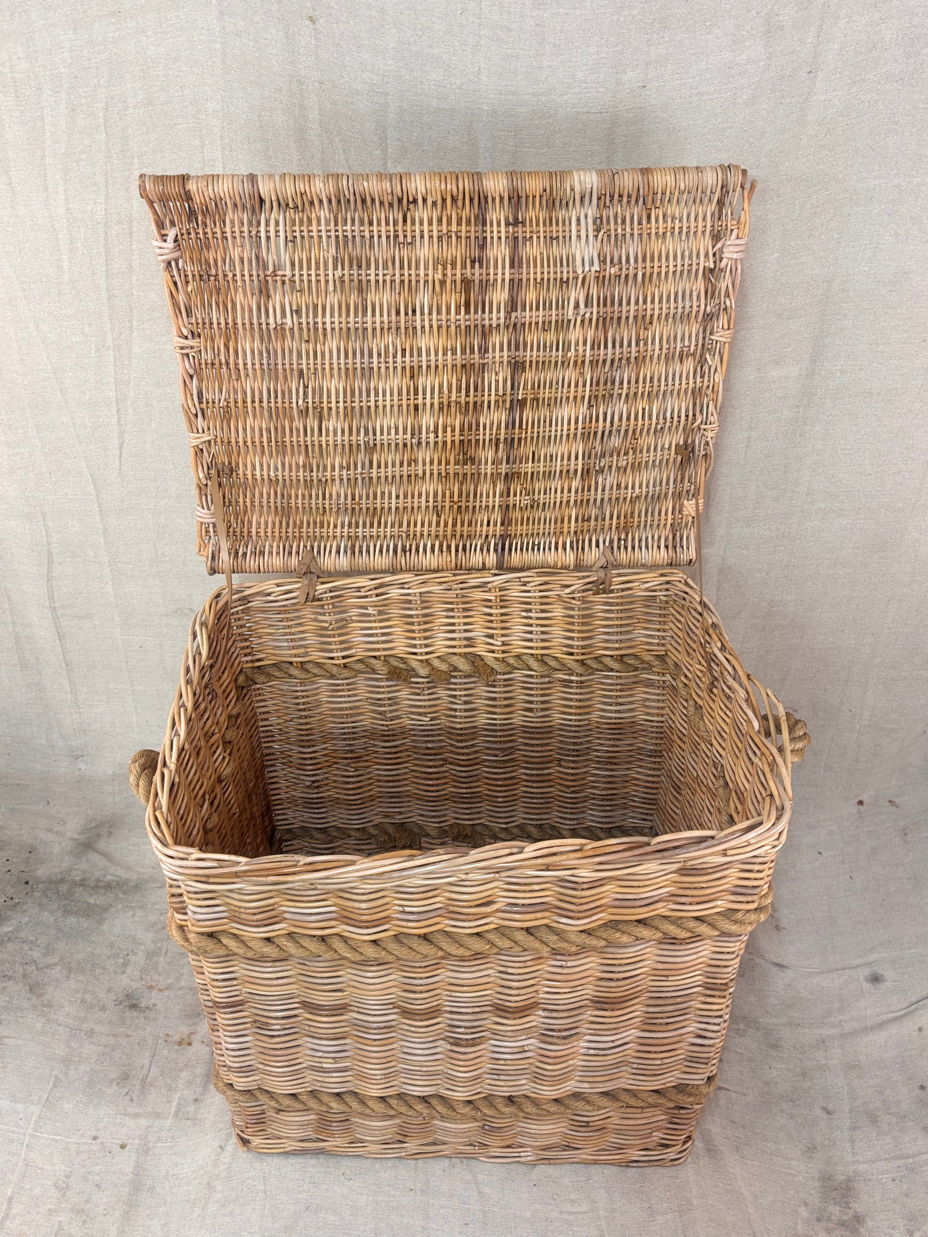 Large wicker storage basket with lid and rope banding, photographed against a neutral backdrop.