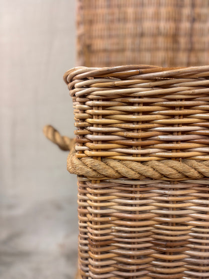 Large wicker storage basket with lid and rope banding, photographed against a neutral backdrop.