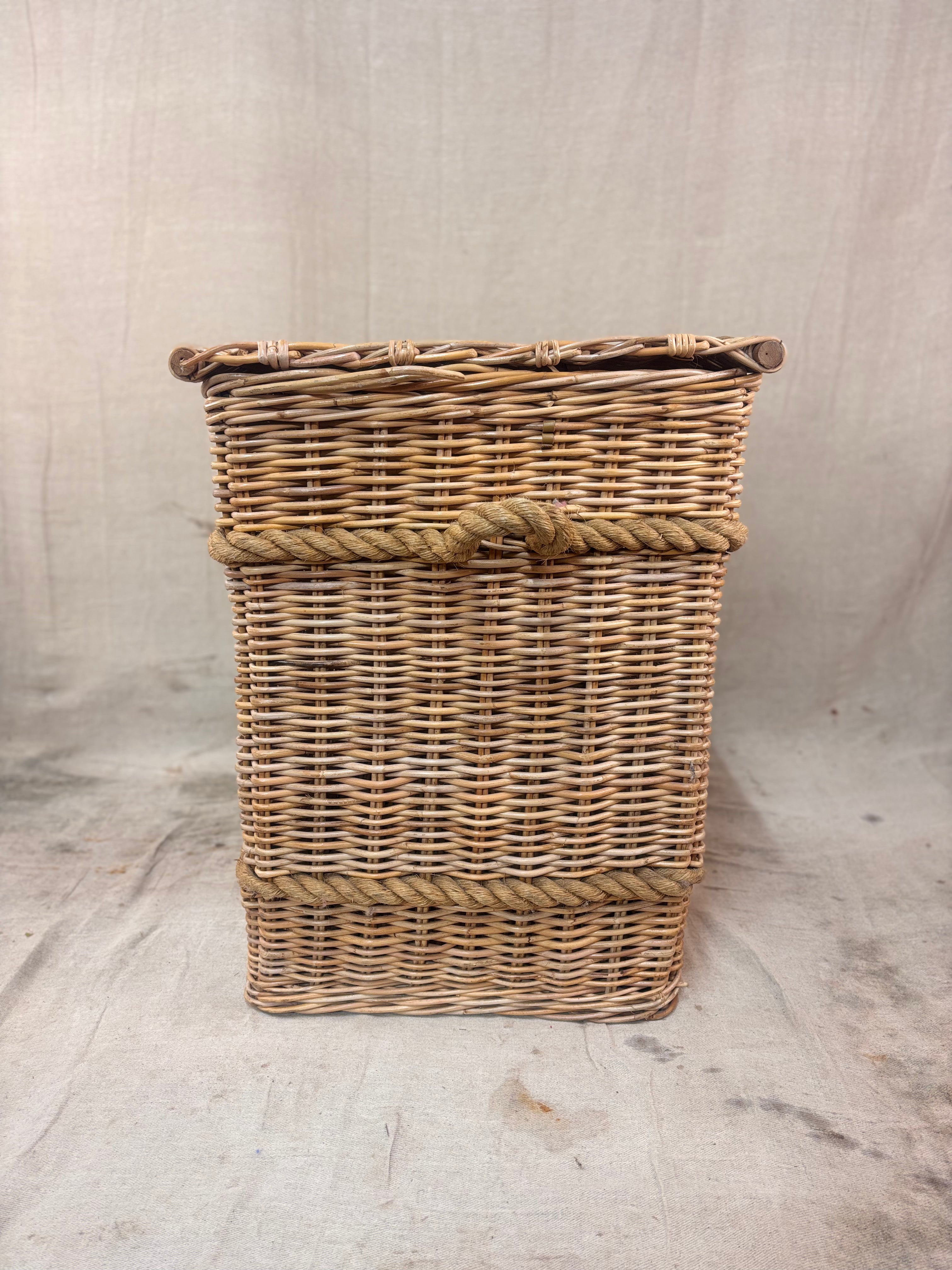 Large wicker storage basket with lid and rope banding, photographed against a neutral backdrop.