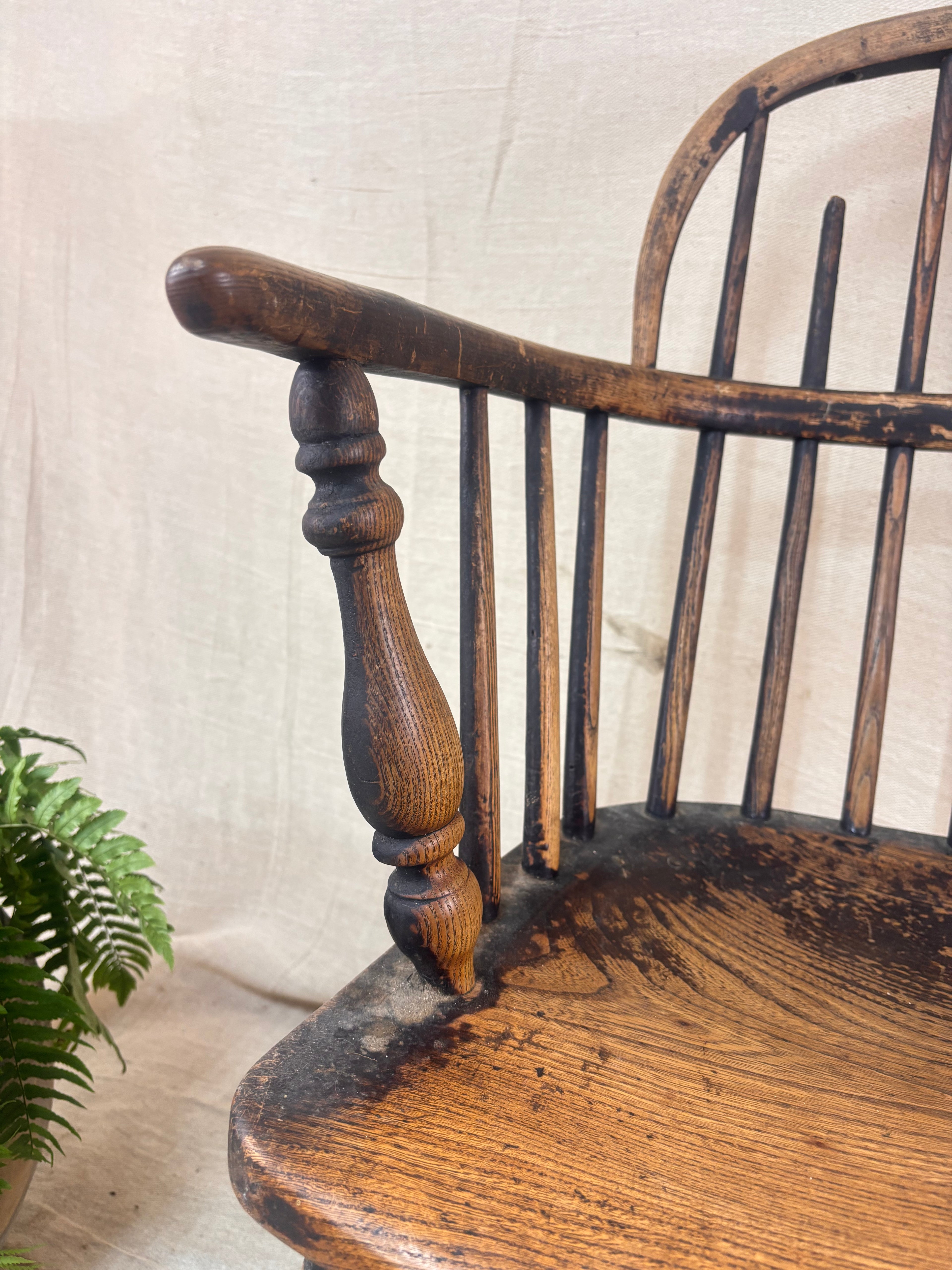 Windsor chair with hoop back, saddled seat, and splayed turned legs shown against a cream fabric background.