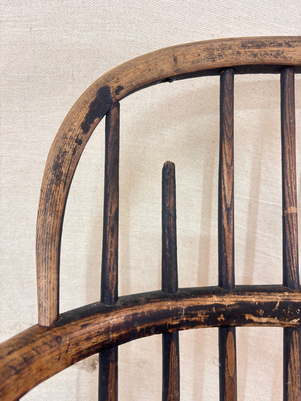 Windsor chair with hoop back, saddled seat, and splayed turned legs shown against a cream fabric background.
